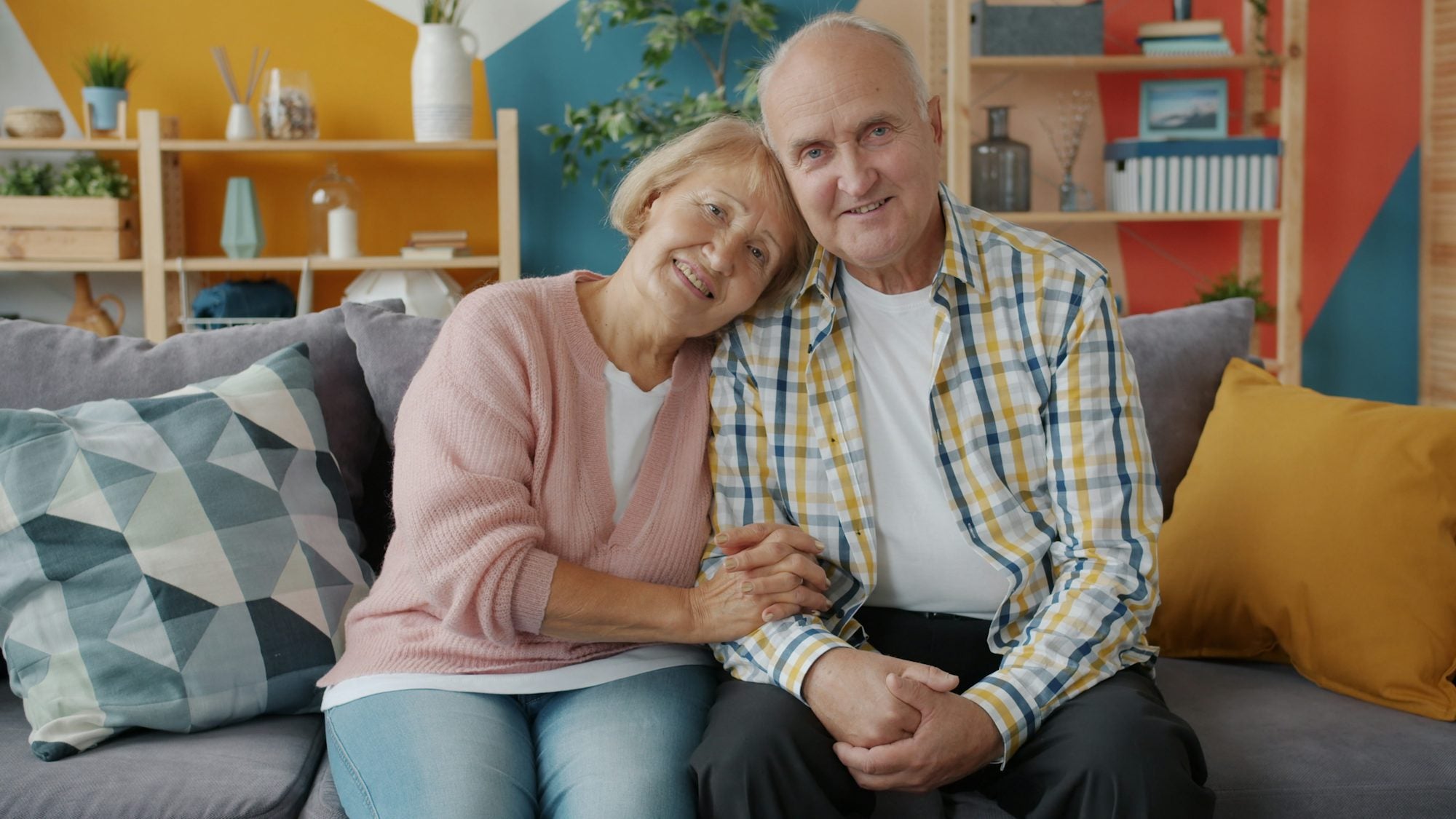 Couple de seniors souriant, confortablement installé chez eux
